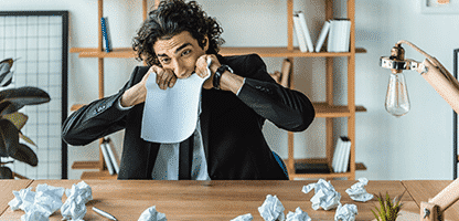 Retrato do empresário estressado mordendo o papel em branco enquanto sentado no local de trabalho no escritório